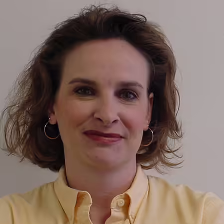 person with brown hair wearing a yellow shirt