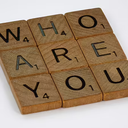 Scrabble pieces that spell out "who are you"