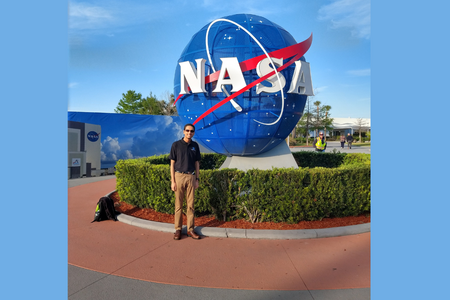 krish nangie poses in front of NASA statue