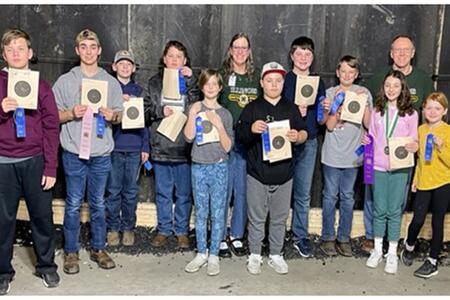 2 adults with 11 youth holding exhibition targets and award ribbons