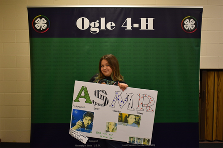 H Coy in front of Ogle 4-H banner with sign