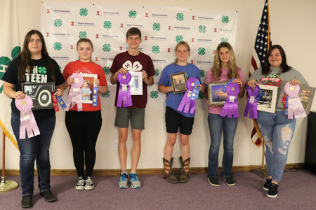 A group of 4-H youth holding photo projects and ribbons.