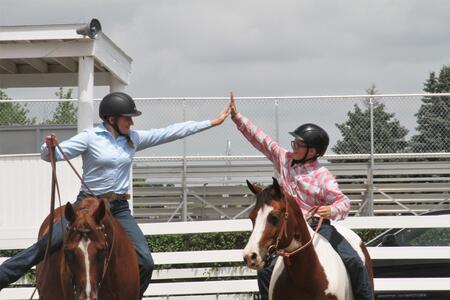 two horse riders high fiving