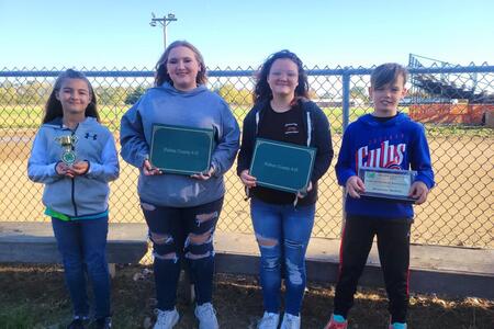 four youth lined up holding their 4-H awards