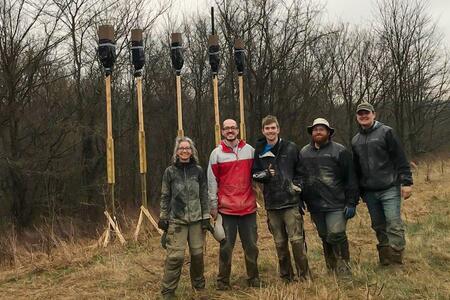 A group of people in front of bat boxes