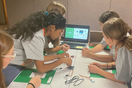 Youth work with a computer and STEM equipment.