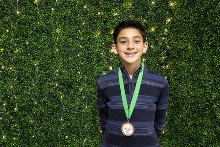 Youth with a medal against a backdrop after winning a 4-H award