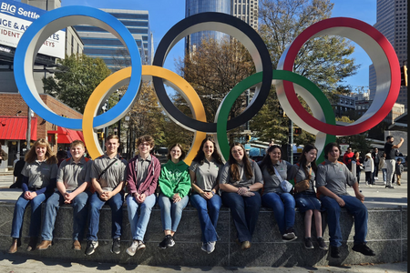 Delegates pose by Olympic rings.