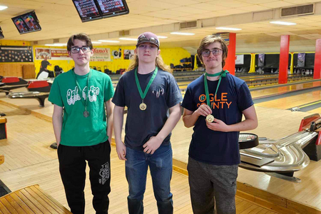 Youth standing on bowling lane with medals 