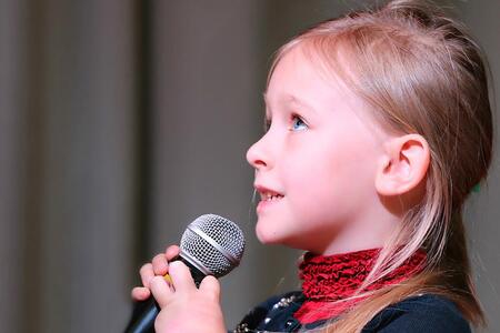 little girl holding a microphone to her mouth