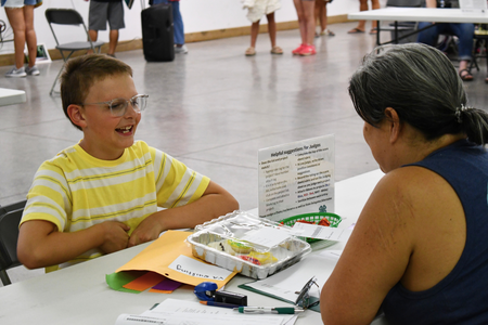 A smiling child talking to an adult about their fair project.