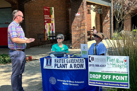 Master Gardeners Jean Geller and Ann Somers sit at a Plant a Row drop off location and chat with University of Illinois Extension Local Foods and Small Farms Educator, Grant McCarty. 