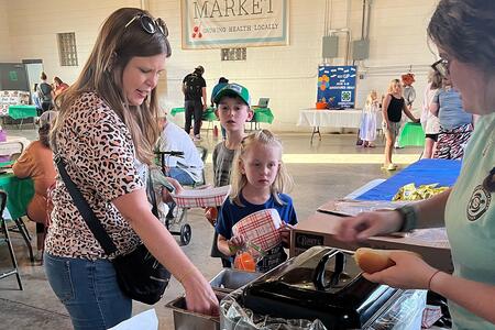 person serving food to a parent with two kids