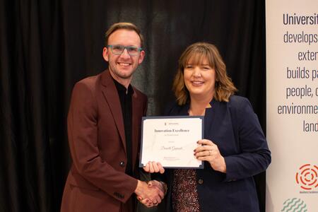 a man and woman holding a certificate hold hands