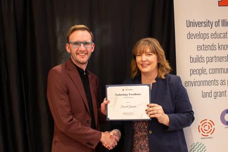 A woman and man stand holding a certificate