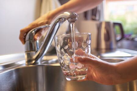 Someone filling a glass of water at the kitchen sink