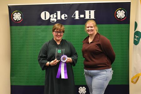 Youth and adult standing in front of banner that says Ogle 4-H.