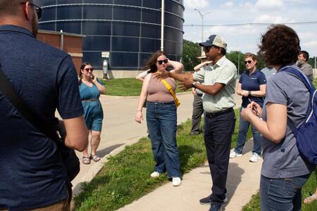 A man speaks to a group of people outside on a tour