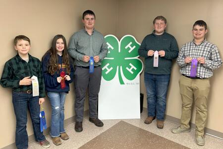 five public speaking winners with their ribbons next to a large 4-H clover