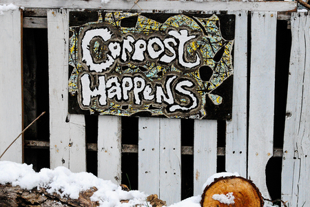 sign on white fence that says compost happens