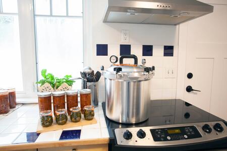 Pressure canner on a stove with canned food next to it