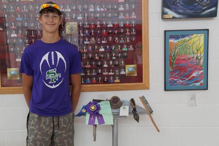 a 4-H member standing next to his welding project