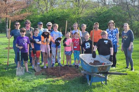 group of 4-H members and volunteers standing around a newly planted tree