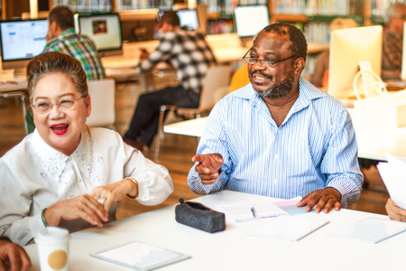 Older adults smiling together at a library table