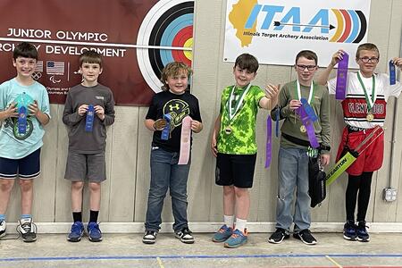 six youth holding award ribbons and medals