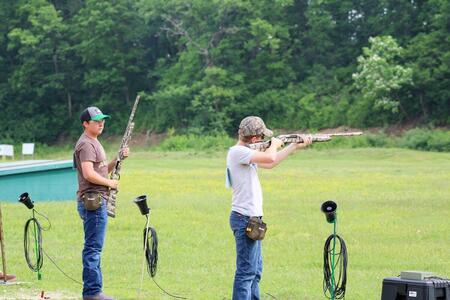 4-H participant holding a rifle and another 4-H participant aiming with their rifle