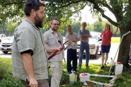 A group of people outside examine a tool