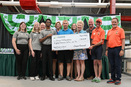 Staff from ACES and COMPEER pose around a giant check.