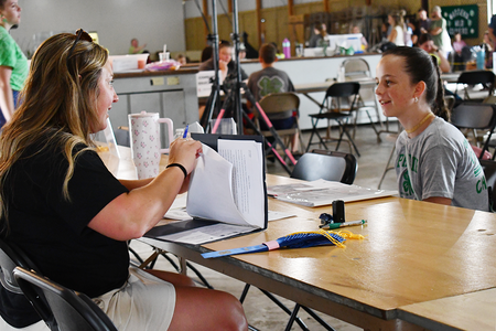 A 4-H'er shares her creative writing project with a judge