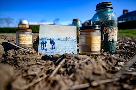 An old black and white photo next to jars of soil in the Morrow Plots