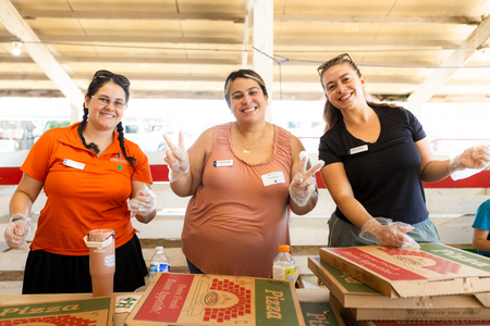 Three people smile for the camera with pizza on the table