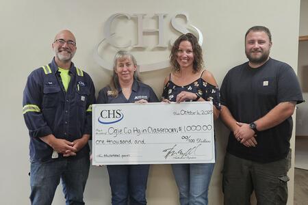 Four adults standing with big mock check