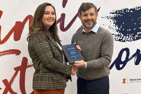 Katie Bell holding plaque next to Extension Director