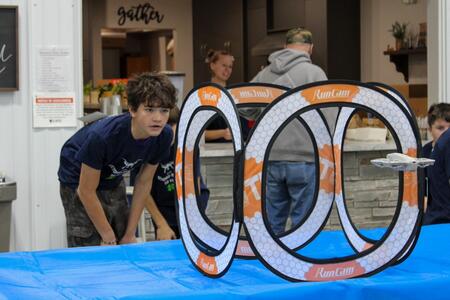 A participant through an obstacle, watching closely to ensure a drone flies through it safely.