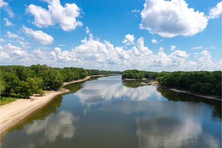 wide river with blue skies and trees bordering