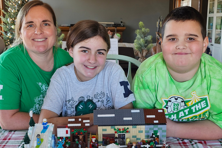 The Naff family poses with a winter village scene made of Lego.
