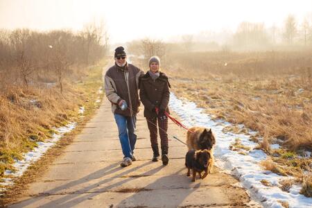 man and woman bundeled up, walking with two dogs 