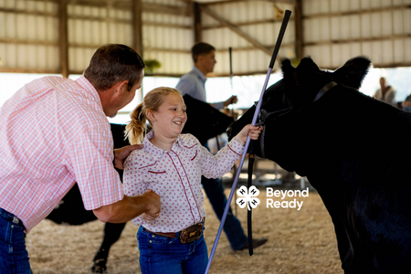 Girl smiles while shaking a judge's hand after showing her steer.