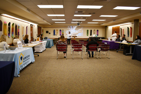 A woman doing a presentation in a room with booths along the wall