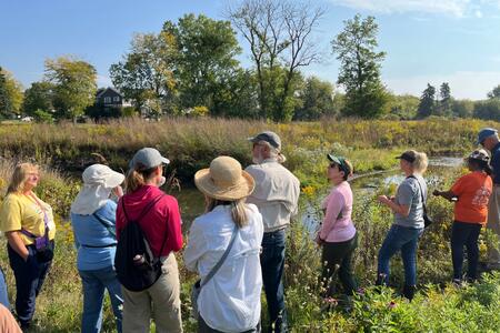 A group of Master Naturalists standing in a field by a river