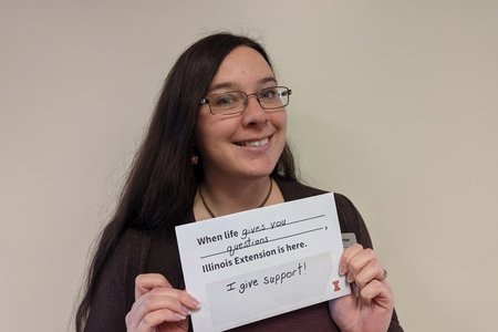 Olivia holds a sign that reads "when life gives you questions, Illinois Extension gives you support"