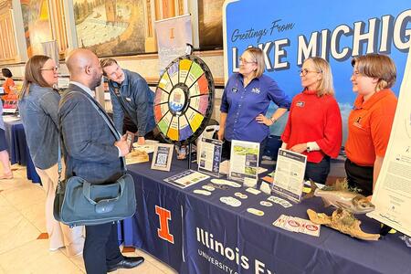 People at a table talk to others a sign in the background says "Lake Michigan"