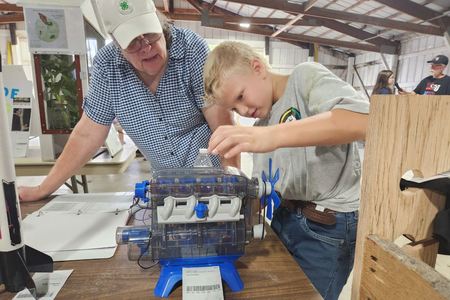 A 4-H member shows a volunteer judge his small engine project