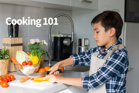 young boy with dark hair and a blue and white plaid shirt cuts up vegetables on a kitchen counter