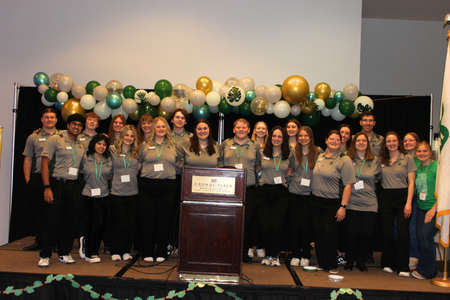 Youth Leadership Team members pose in front of leaf balloons. 