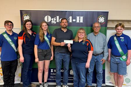 Group of youth and adults standing with check.